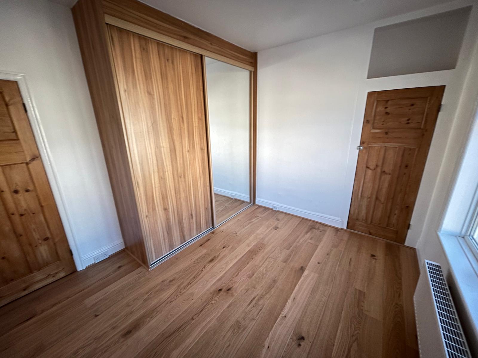 Bedroom with fitted sliding wardrobe, engineered oak flooring and stripped pine doors