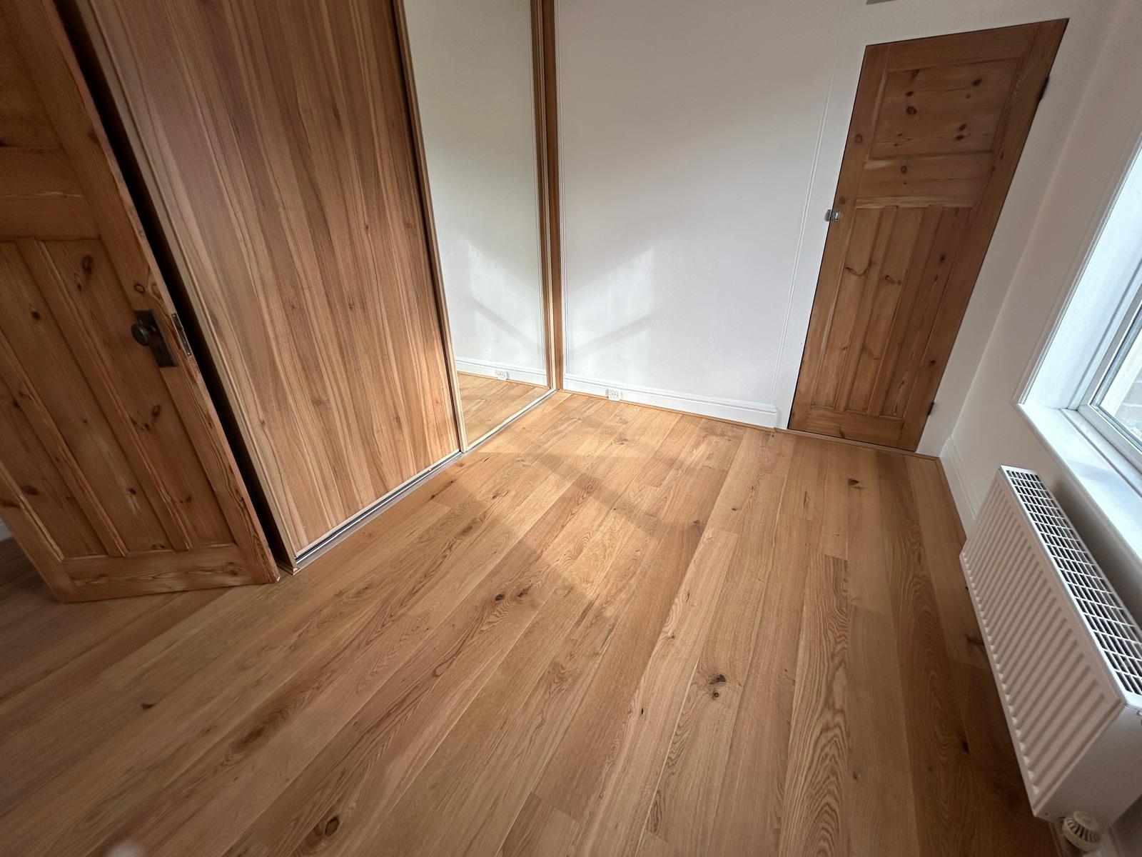 Bedroom with engineered oak flooring, fitted wardrobe and restored pine doors