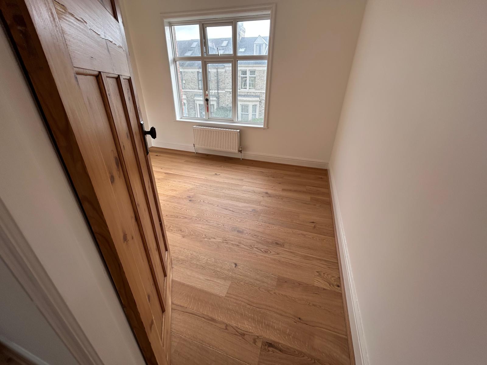 Refurbished bedroom with new oak flooring and a view over neighbouring terraced streets