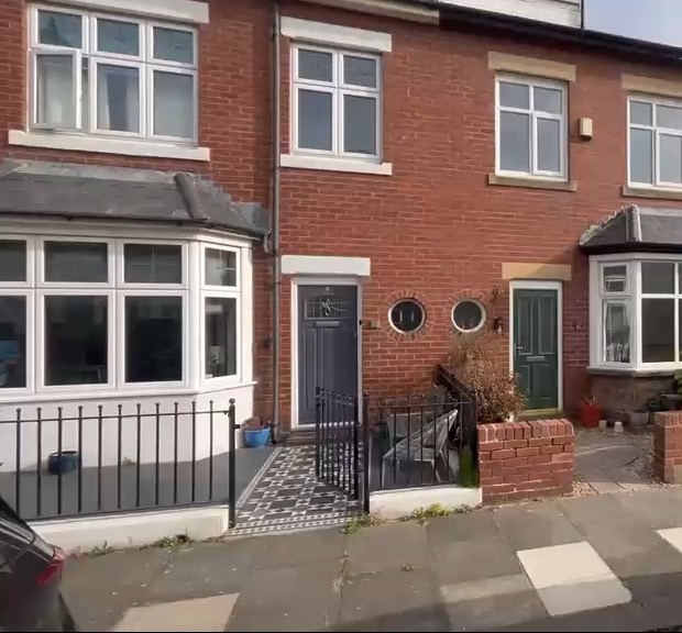 Front elevation of a red-brick terraced house with bay window