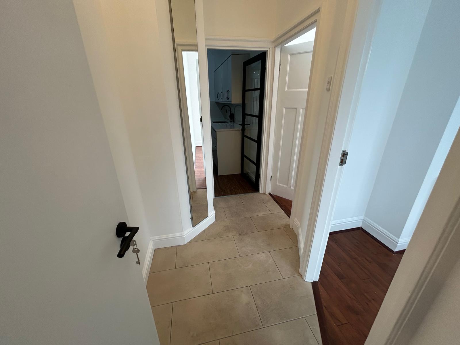 Tiled hallway with painted joinery and a black-framed glazed door, refurbished by ORA Property Services