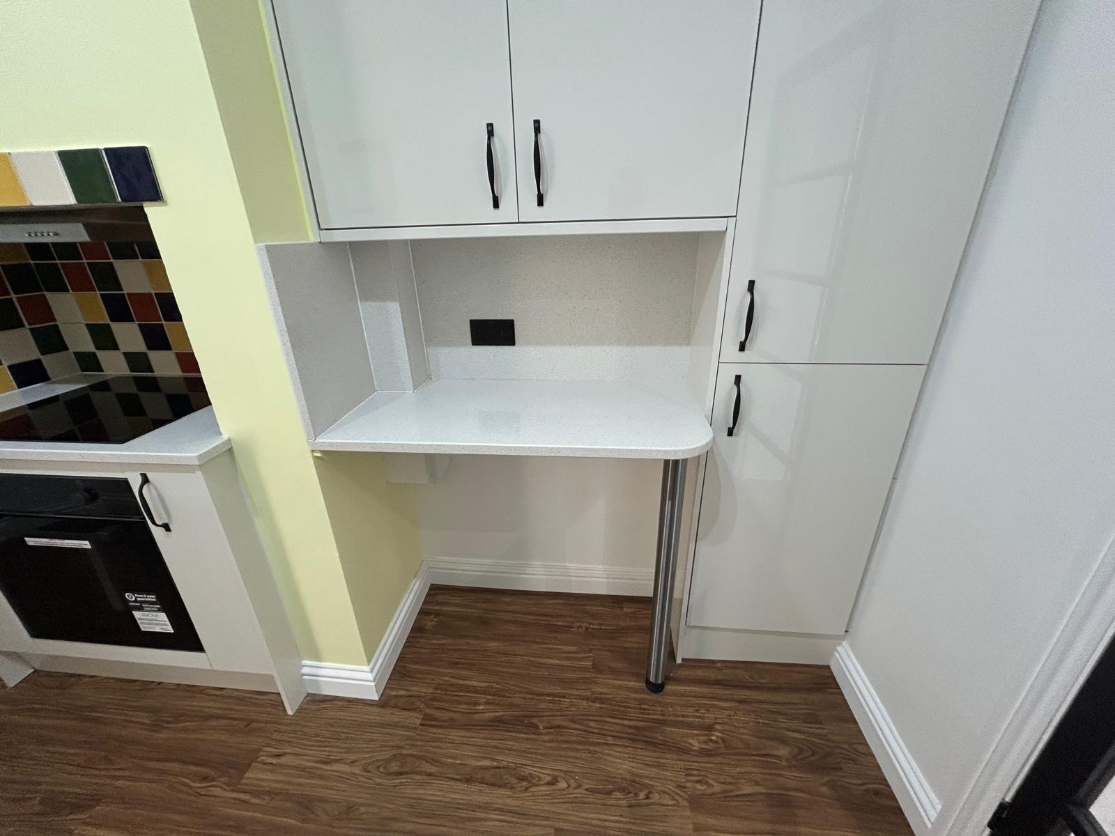Built-in breakfast bar with quartz top between white gloss tall units