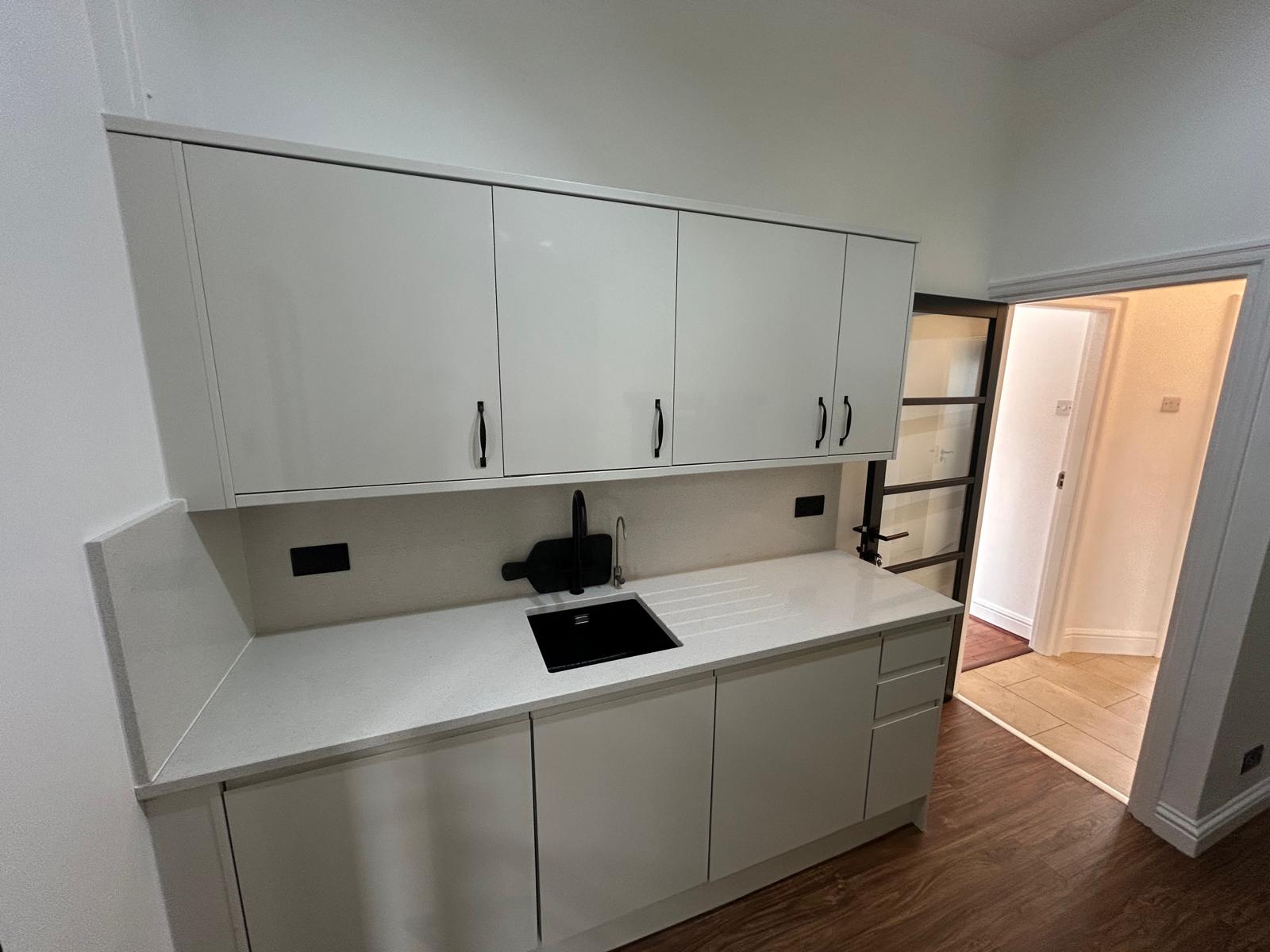 White gloss kitchen with quartz worktop, black undermount sink and black handles
