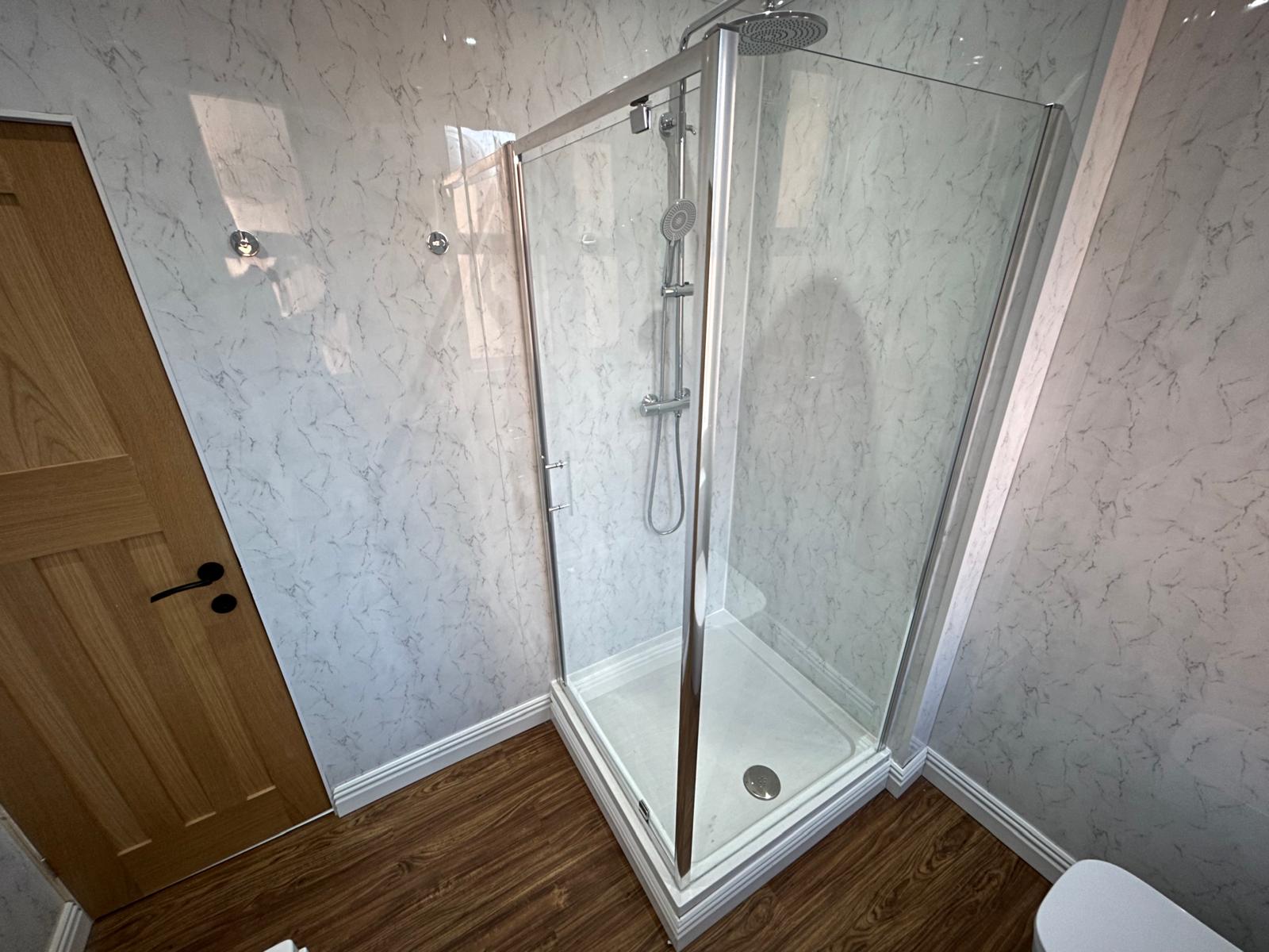 Shower room with glass enclosure and marble-effect wall panels, refurbished by ORA Property Services