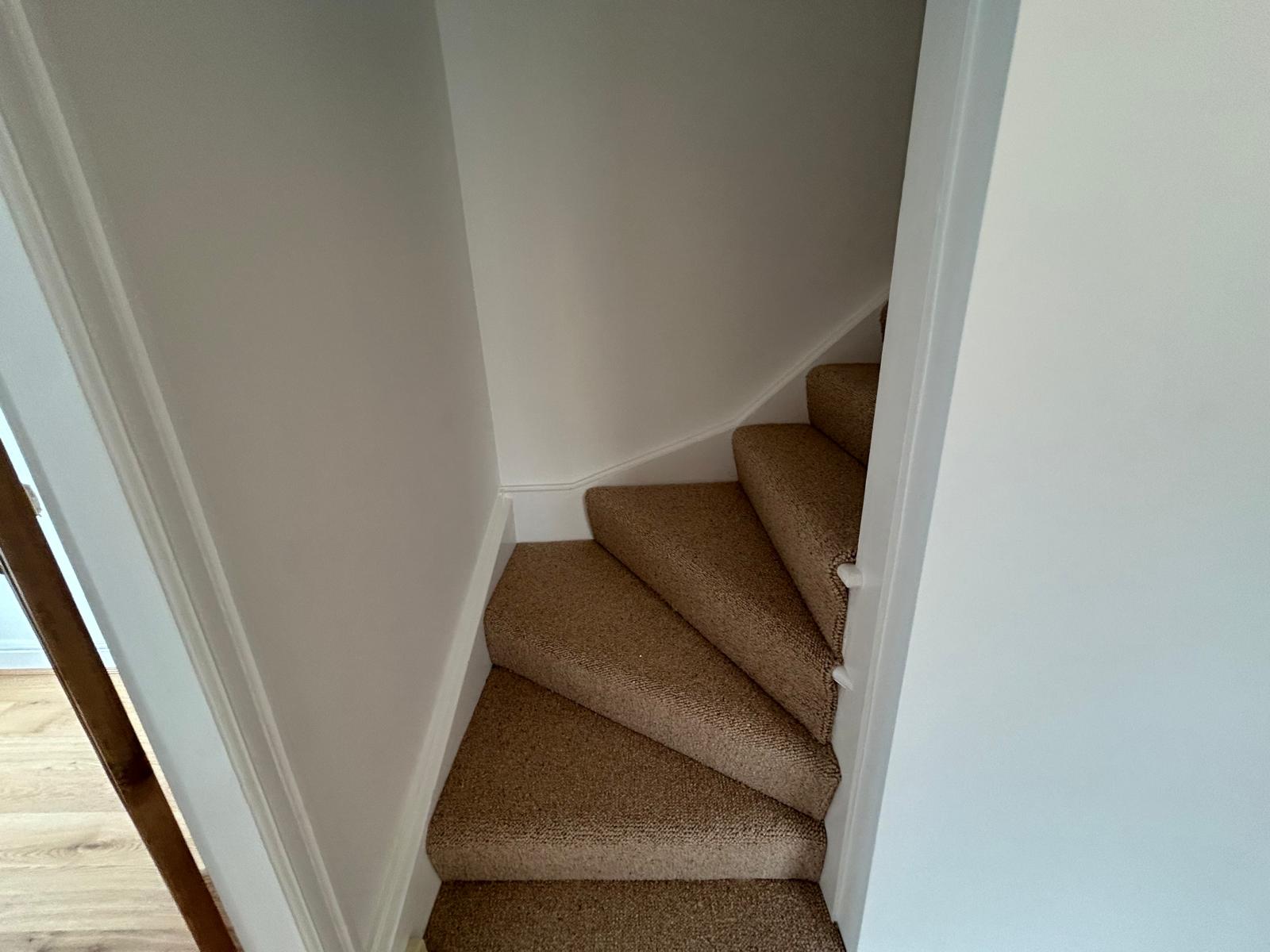 Winding staircase with new carpet and painted walls